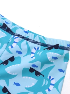 Detail of boys blue swim shorts with cartoon shark print and reinforced elastic waistband
