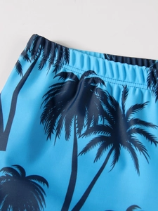 Detail of boys blue swim shorts featuring tropical palm tree prints and elastic waistband