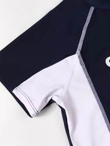 Detail of flatlock stitching and white lettering on navy blue kids rash guard