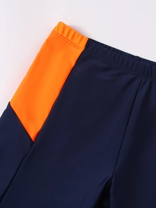 Detail of navy boy's trunks with orange side panel and elastic waistband stitching