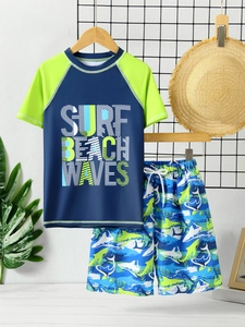 Detail of two-piece boys swimwear set with shark print shorts and surf rash guard