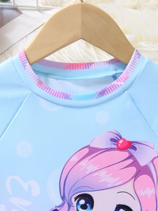Detail of blue girl's swimsuit showing cartoon print and pink striped neckline trim