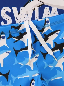Detail of boys' blue swim trunks with shark prints and elastic drawstring waistband