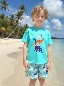 Short sleeve boy's swimsuit set with dinosaur print on beach against blue sky