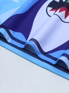 Zoom sur les coutures de l'ourlet et l'imprimé requin du maillot de bain bleu enfant