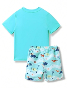 Detail of boys' two-piece swimsuit featuring a cartoon dinosaur print and teal short sleeves