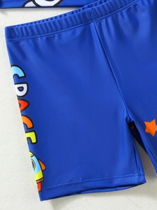 Primer plano de bañador azul para niño con letras espaciales y estampado de cohetes