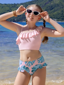 Detail of girls two-piece swimsuit with ruffled shoulder strap and palm leaf print