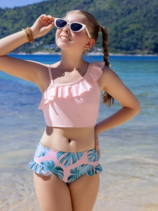 Detail of girls two-piece swimsuit with ruffled single shoulder top and tropical leaf print