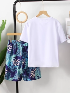 Detail of boys' short sleeve swim top and tropical leaf print shorts on hanger