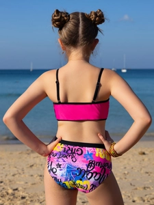 Rear view of girls two-piece swimsuit with pink top and graffiti print bottoms on the beach