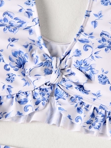 Detail of girls floral swimsuit featuring chest knot and ruffled hem with blue prints