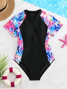 Detailed view of girls' one-piece swimsuit with tropical leaf print and front zipper