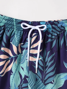 Detail of tropical leaf print on boy swim shorts with elastic waist and white drawstring