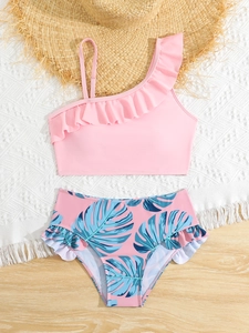 Flat lay of girls' two-piece swimsuit with ruffled pink top and tropical leaf print bottom