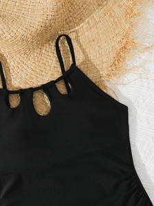 Details des schwarzen Mädchen-Badeanzugs mit Cut-out-Design und Trägern auf Strohhut-Hintergrund