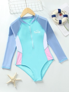 Flat lay of girl long sleeve one piece swimsuit with SUMMER print on wooden background
