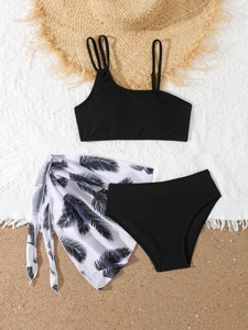 Three-piece girls swimwear set with palm leaf sarong on a beach-themed background