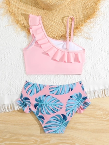 Close-up of girls' pink ruffle swimsuit top and tropical leaf print bikini bottoms