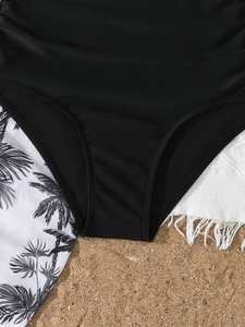 Detail einer schwarzen High-Waist-Badehose mit seitlicher Raffung auf Strandtuch