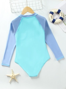Flat lay of long-sleeved girls swimsuit with blue-purple contrast on white wooden background