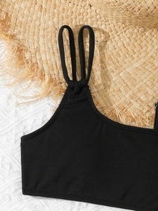 Detail of black ribbed girls' bikini top with unique double-ring straps and fabric texture