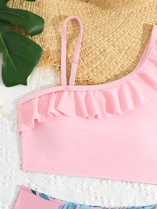 Detail of pink ruffled bikini top with tropical plant print and summer props