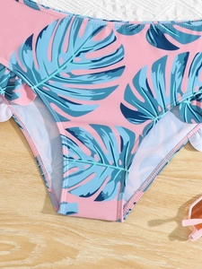 Detail view of pink bikini bottoms with blue tropical leaves and ruffled side edges