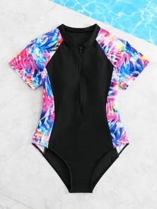 Close-up of tropical leaf prints and smooth zipper on black girls' one-piece swimsuit