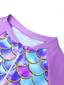 Close-up of children's mermaid swimsuit featuring purple scale print and white zipper