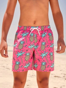 Detail of pink boys' beach shorts with blue palm trees and yellow pineapple prints