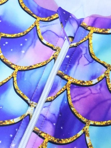 Detail view of colorful mermaid scales print with durable white front zipper closure