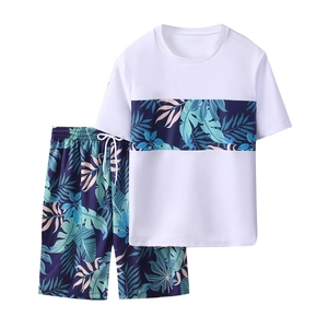 Two-piece boys swimwear set with white short-sleeve top and tropical leaf print shorts