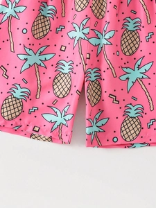 Detailed close-up of pink kids beach shorts with tropical pineapple and palm tree prints