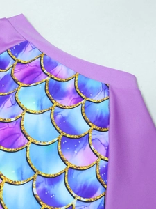 Detail of purple mermaid scales pattern with gold glitter and starry accents on swimsuit