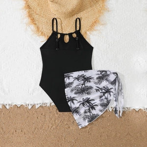 Mädchen Badeanzug in Schwarz mit Mesh-Sarong und Palmenmuster auf Strandhintergrund