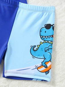 Dettaglio dei pantaloncini da bagno per bambini con stampa dinosauro e patchwork blu