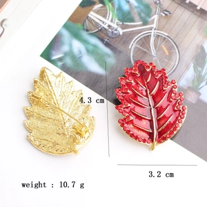 Dettaglio della spilla a foglia rossa con dimensioni 4,3x3,2cm e chiusura di sicurezza