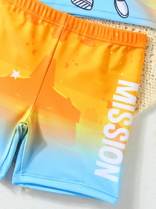 Dettaglio del costume da bagno bimbo sfumato con stampa MISSION e tessuto ad asciugatura rapida