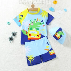 Three-piece boy swimming set with blue short sleeve top, shorts and dinosaur cap
