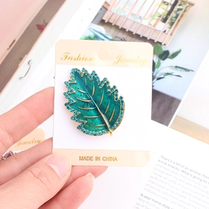 Dettaglio della spilla a foglia verde con strass blu su carta Fashion Jewelry