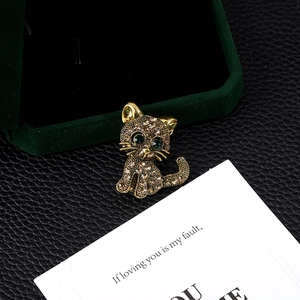 Exquisite cat brooch with brown rhinestones and green eyes on black leather background