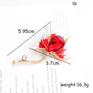 Elegant gold magnolia flower brooch with red enamel petals and teardrop crystal stone