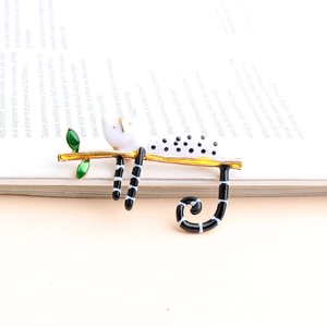 Cute white polka dot cat on a golden branch brooch with green enamel leaves on a book