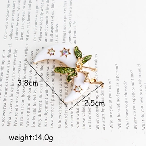 Broche fée de lune avec ailes vertes et strass étoilés sur fond de livre vintage