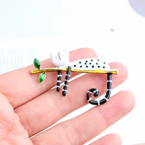 Zinc alloy cat brooch with colorful enamel finish perched on a golden branch