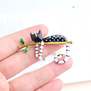 Cute black and white enamel cat brooch with gold branch and green leaves on hand
