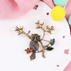 Détail de la broche hibou rétro avec cristaux et perles sur une assiette décorative
