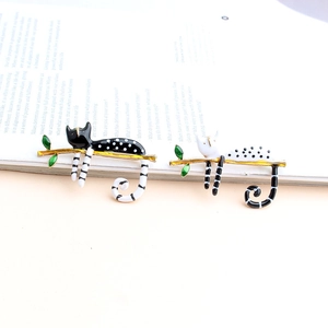 Charming enamel cat brooches on a golden branch set against a vintage book background