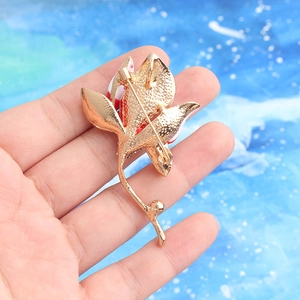 Creative crystal flower brooch with red enamel and gold back pin shown in hand